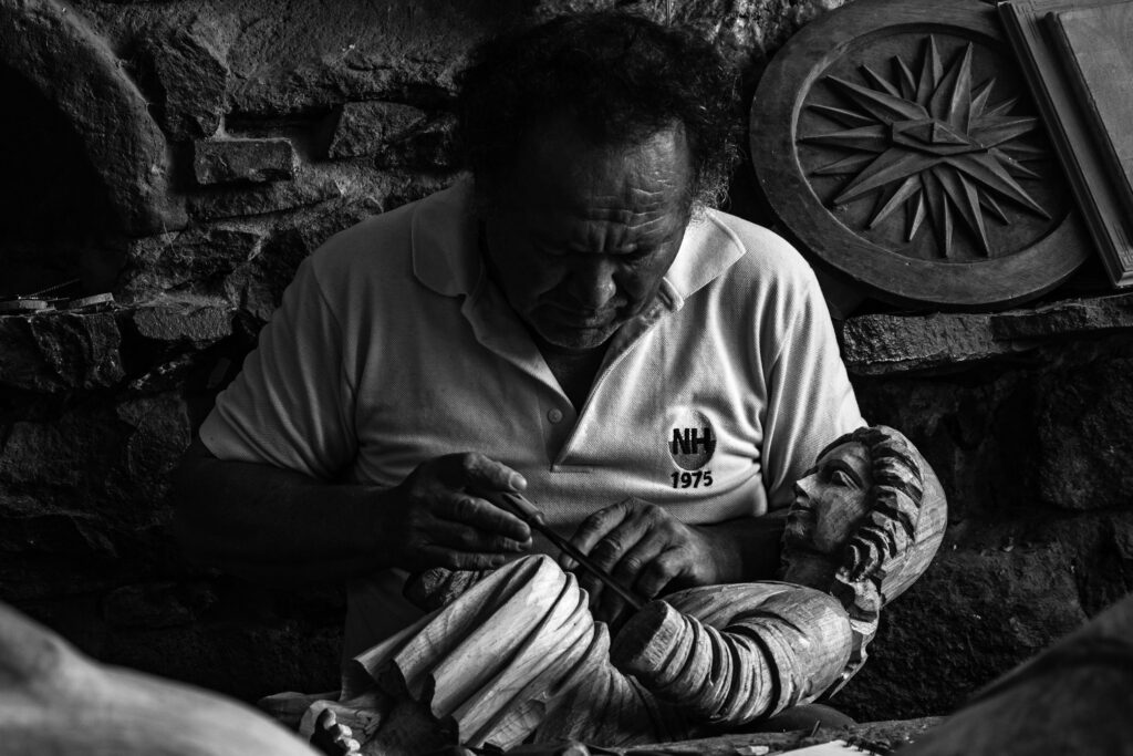 Artigianatoprime | Trova i migliori artigiani in tutta Italia Black and white photo of a craftsman meticulously carving a wooden sculpture in Ibarra, Ecuador.
