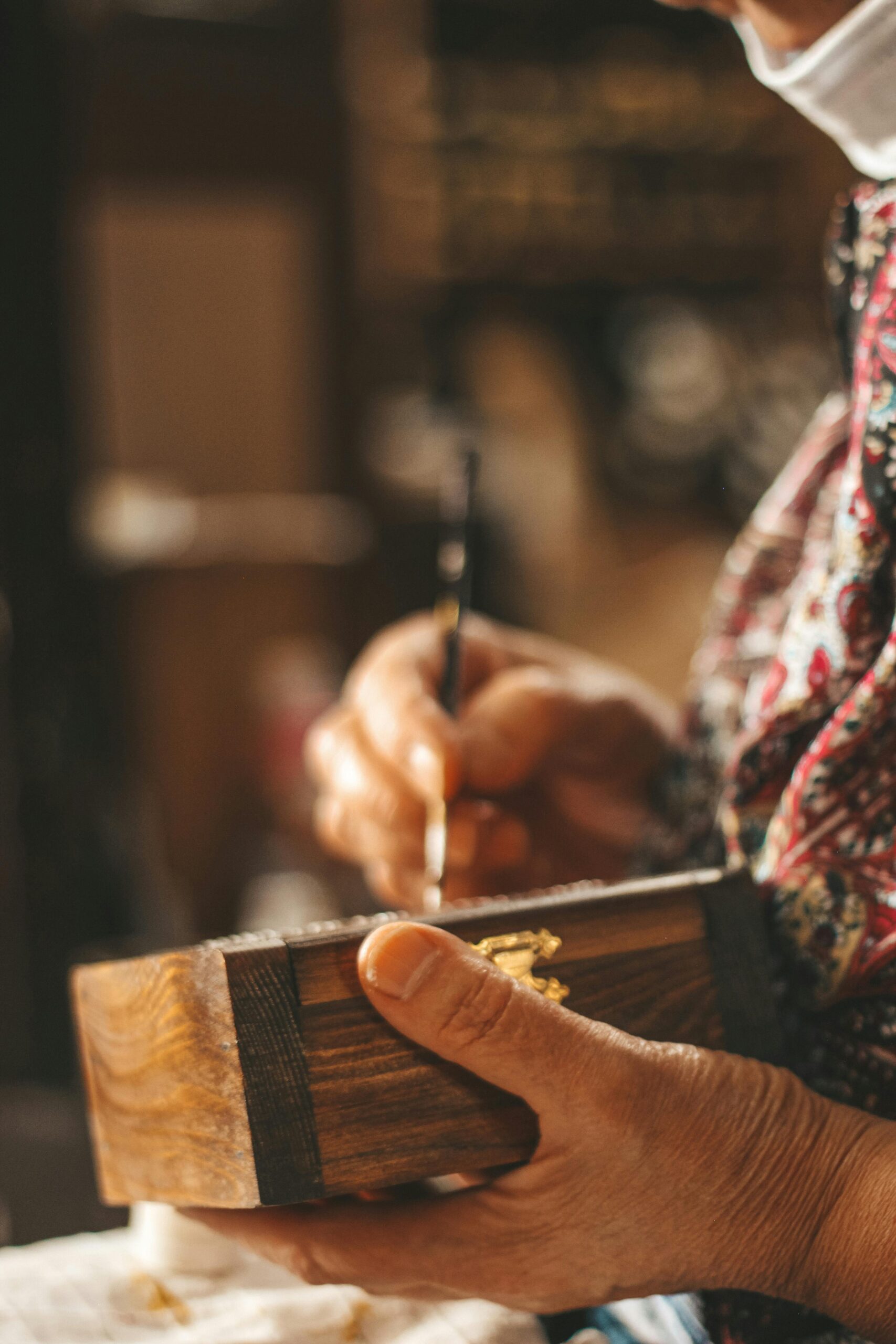 Artigianatoprime | Trova i migliori artigiani in tutta Italia Close-up of an artisan hand painting a wooden box, highlighting craft and detail.